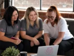 Three BelRose Group team members working together around a laptop
