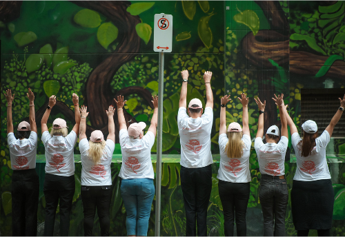 Eight BelRose team members together with their hands raised
